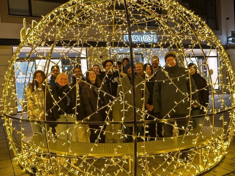 Students standing behind circular structure with twinkle light